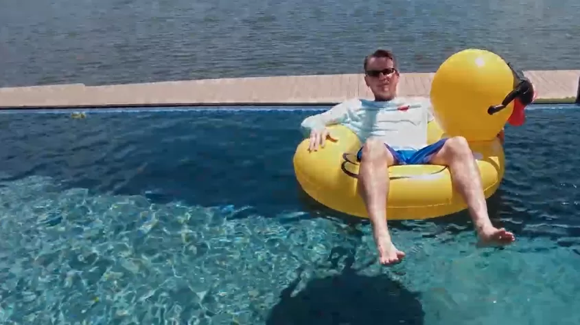 man in inflatable rubber duck in pool 
