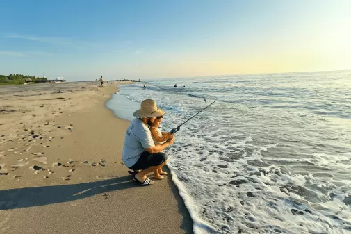 A family fishing on a beach next to the ocean