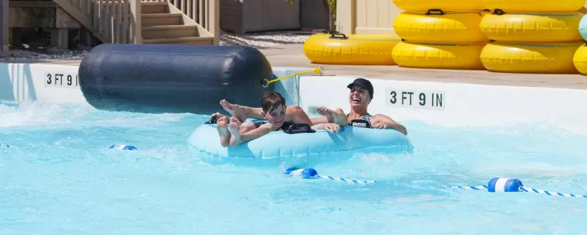 A mother and child float in the pool on a tube after completing a water slide